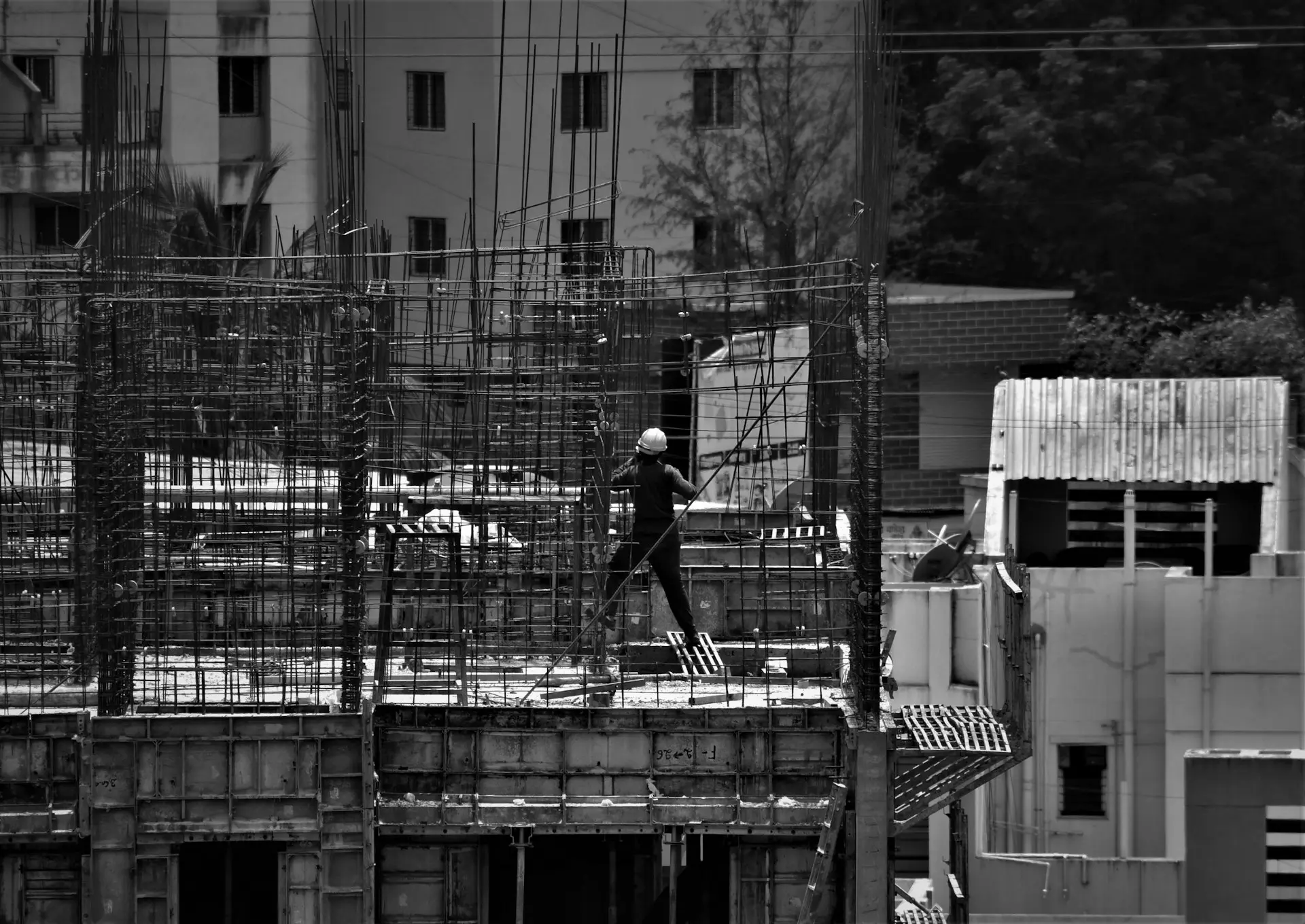 grayscale photo of man in black jacket and pants standing on building